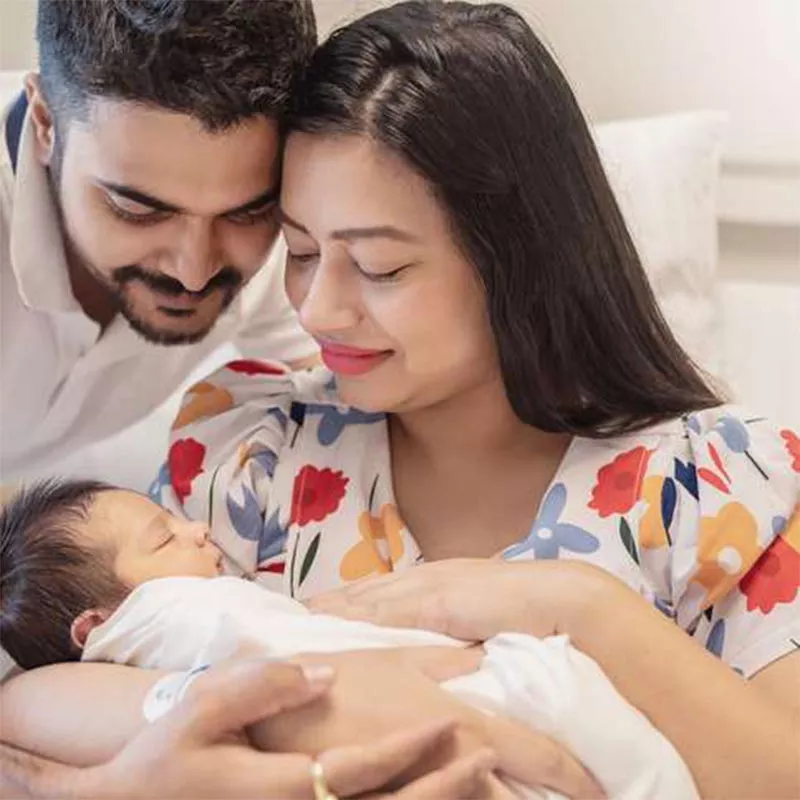 Middle Eastern mother and father smiling at newborn