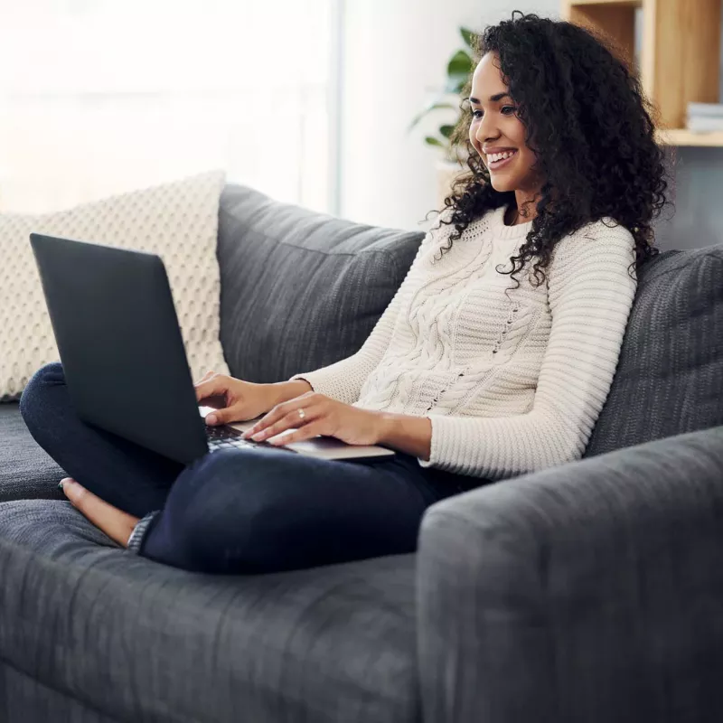 Young woman with laptop sitting on couch