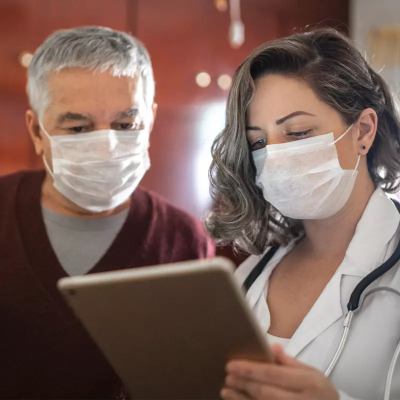 Man looking at chart with a doctor while both are wearing masks.