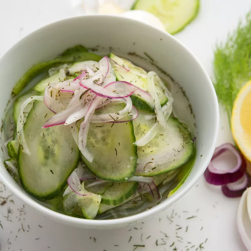 Bowl of cucumber relish with cucumber and lemon garnishes