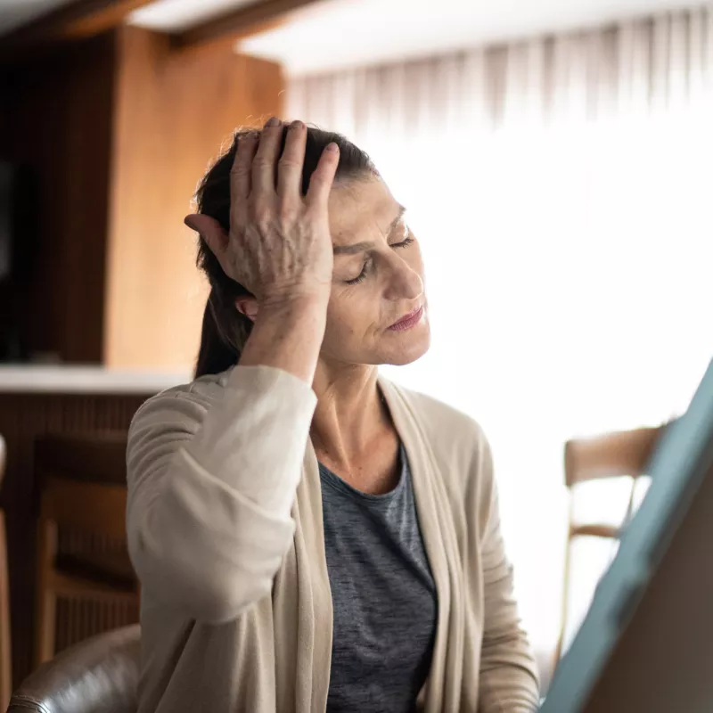 An older woman holding her hand to her head.