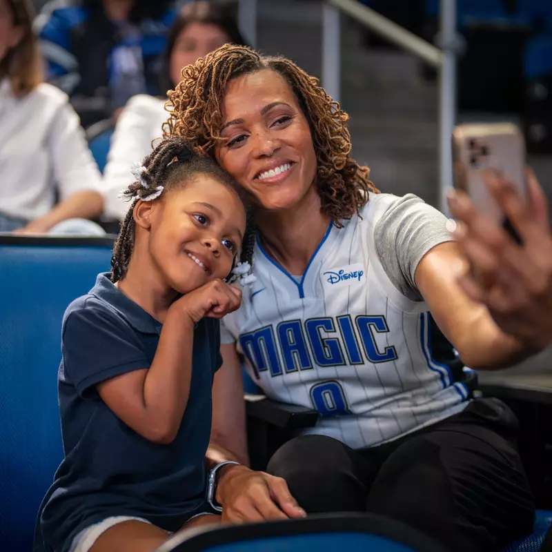 Mother and daughter taking selfie at Orlando Magic game.