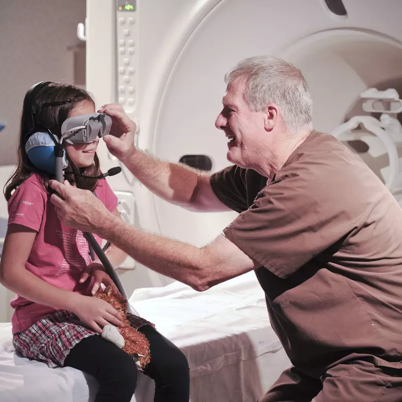 A male nurse puts MRI goggles on a girl.