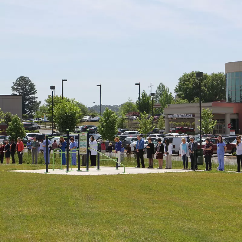 AdventHealth staff are gathered outside of a hospital praying.