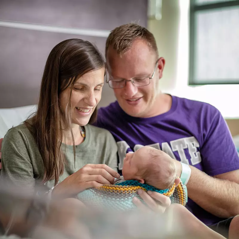 New parents hold their newborn in the hospital.