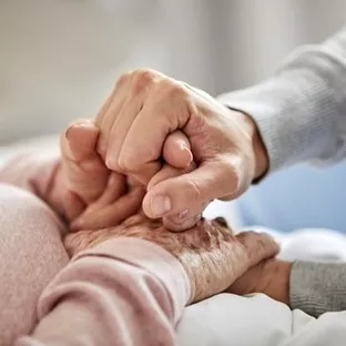 People holding hands at a patient's bedside