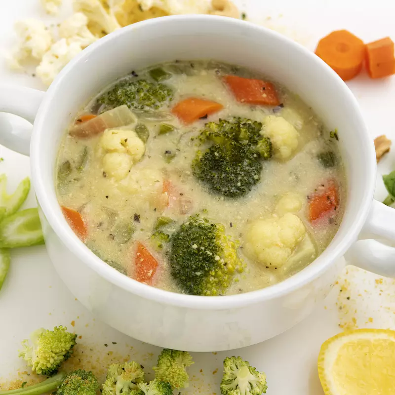 Bowl of vegetable soup with lemon and celery garnishes