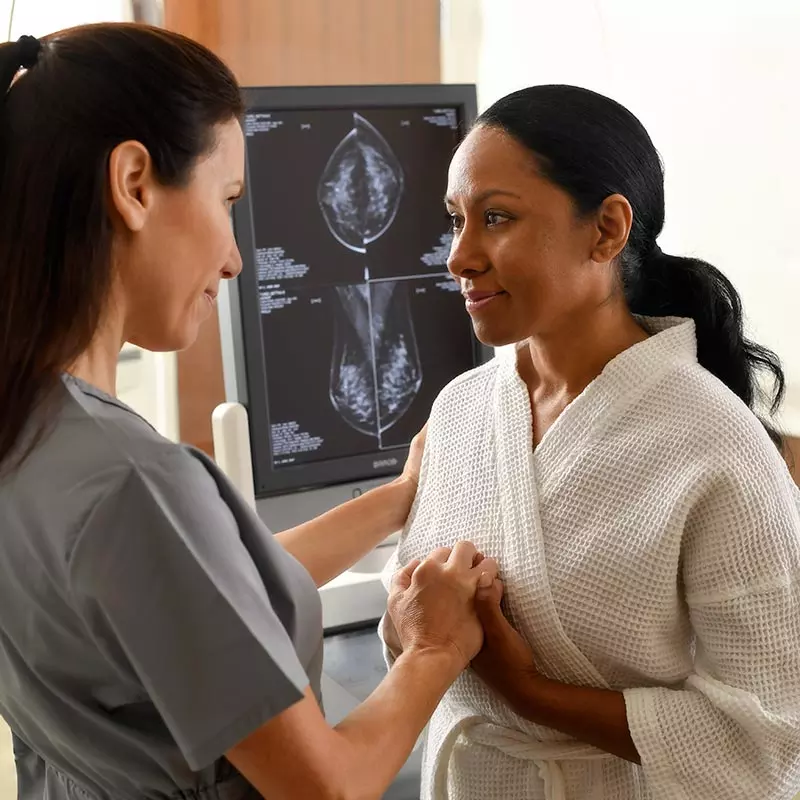 Nurse holding hands with a patient getting a scan