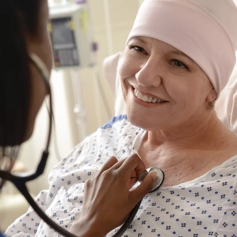 An adult female cancer patient receives treatment from a nurse.