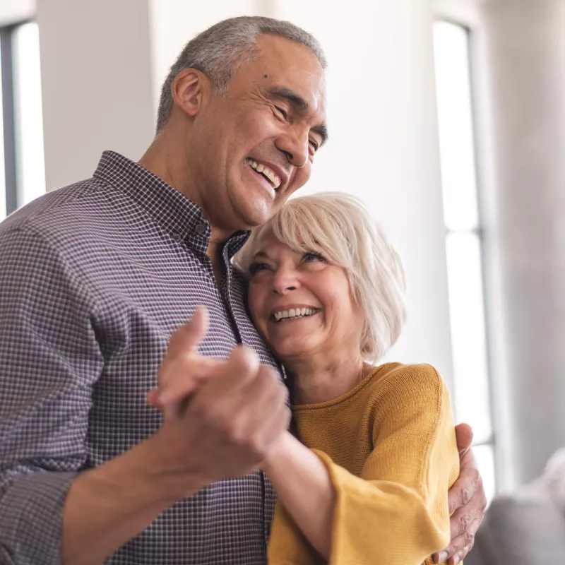 Older Couple dancing together while at home.