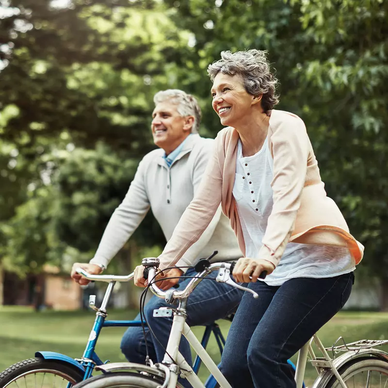 Older couple riding bicycles outdoors.