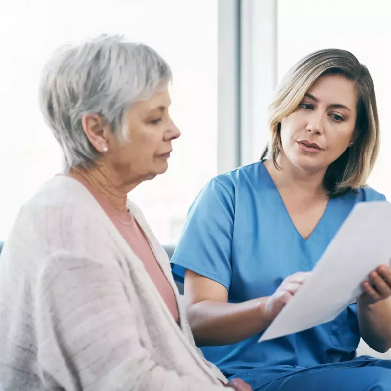 Older female patient looking at a document with her nurse
