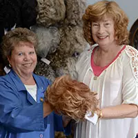 a photo of two women holding a wig