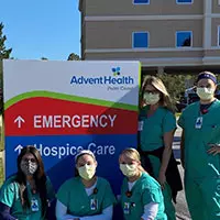 a group of health care workers in front of a sign