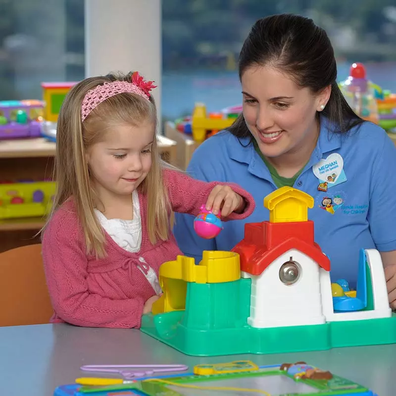 Pediatric specialist and child playing with toy house
