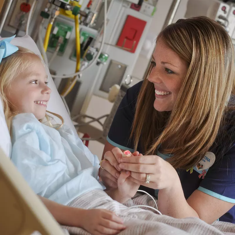 Smiling pediatric nurse with a little girl in a hospital bed