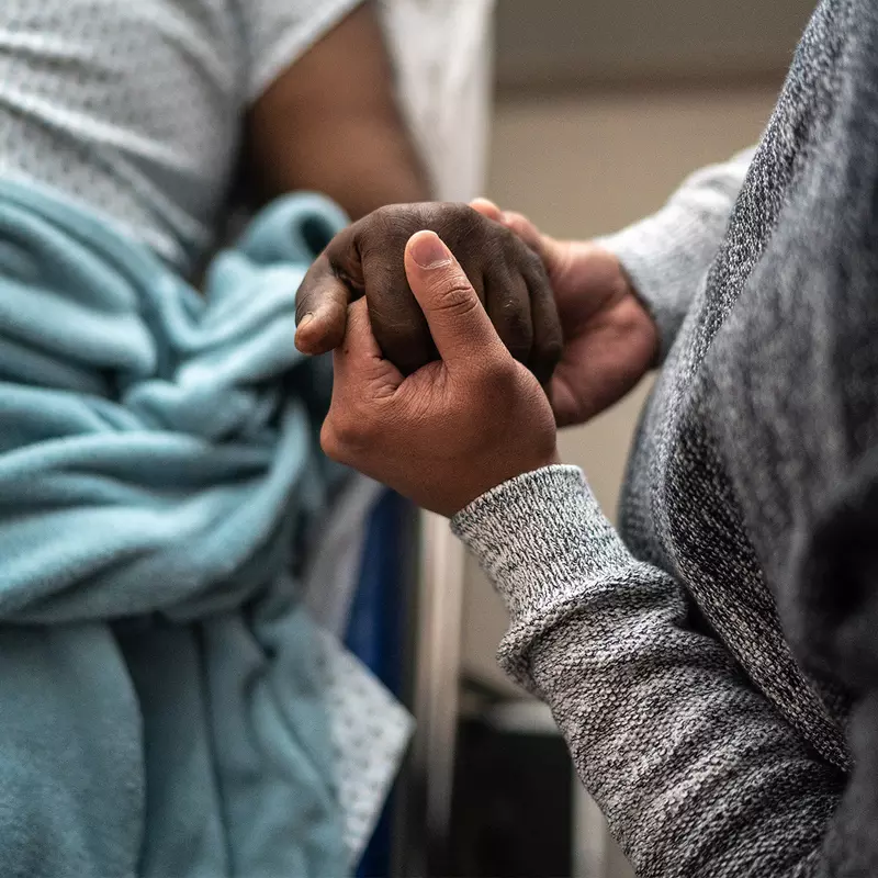 Man holding a patient's hand.