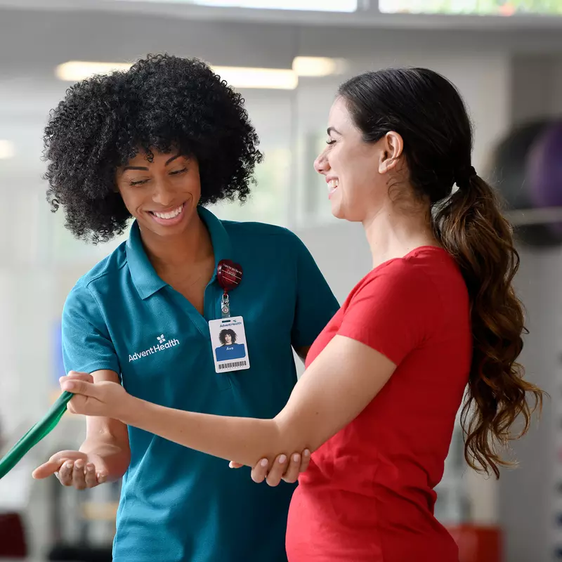 Physical Therapist guiding a woman patient through an exercise to strengthen arm.