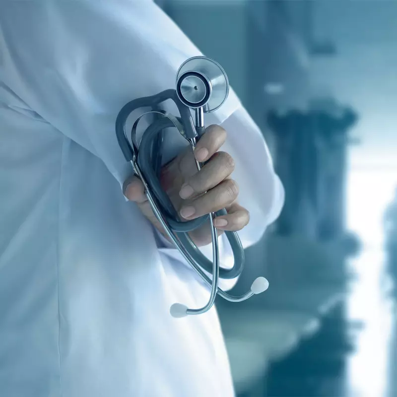 Physician holding stethoscope in hallway.
