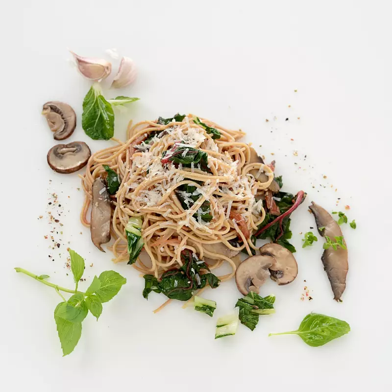 a serving of whole wheat angel hair pasta mixed with greens and mushrooms