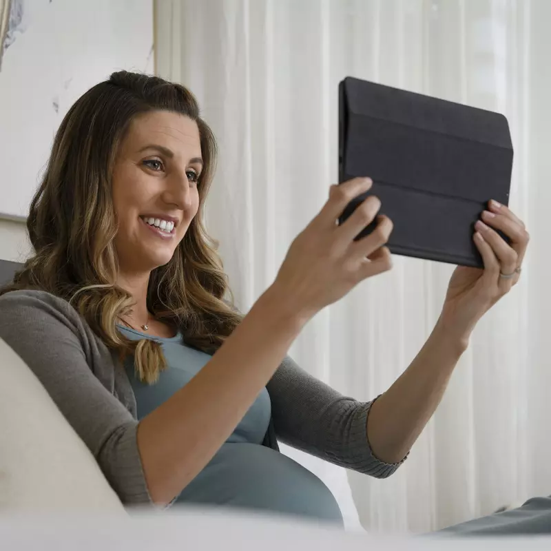 A pregnant woman watches a video on a tablet