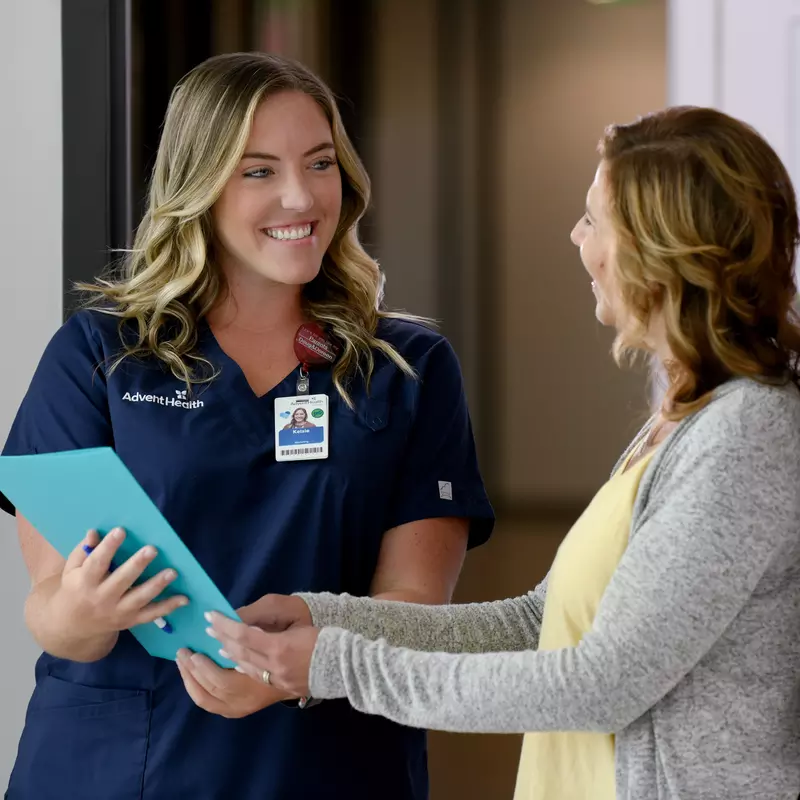 A Primary Care+ Nurse Goes Over Paperwork with a Smiling Patient