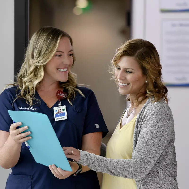 A Primary Care+ Nurse Goes Over Paperwork with a Smiling Patient