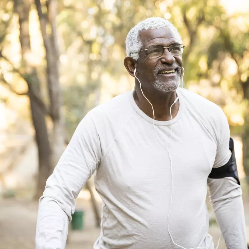 Older African American man walking outdoors.