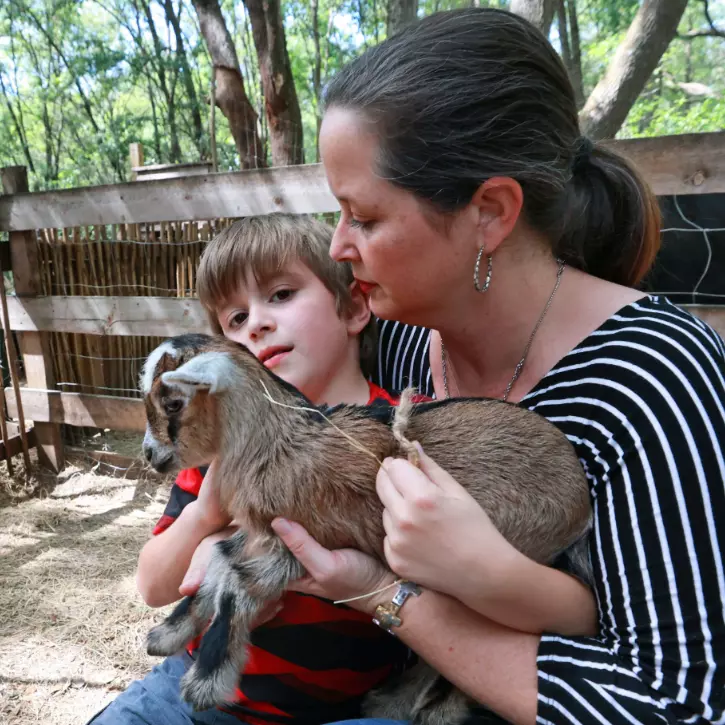 Cameron Munoz and one of her sons snuggle a baby goat at Puzzle Ranch in Sorrento, Florida.