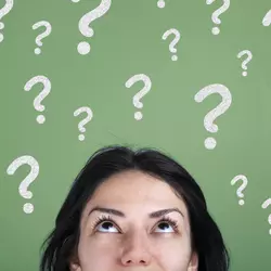 A woman looks upward, with question marks floating above her.