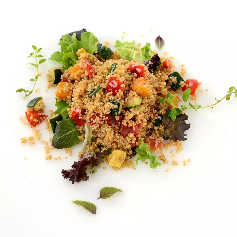a large scoop of cooked quinoa, mixed with colorful squash and peppers