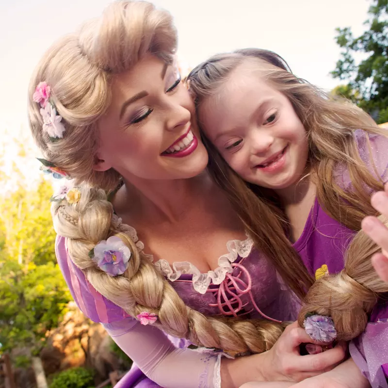 Disney Rapunzel character in the park with a young girl.