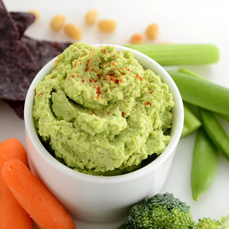 Side dish of edamame hummus with some carrots and chips