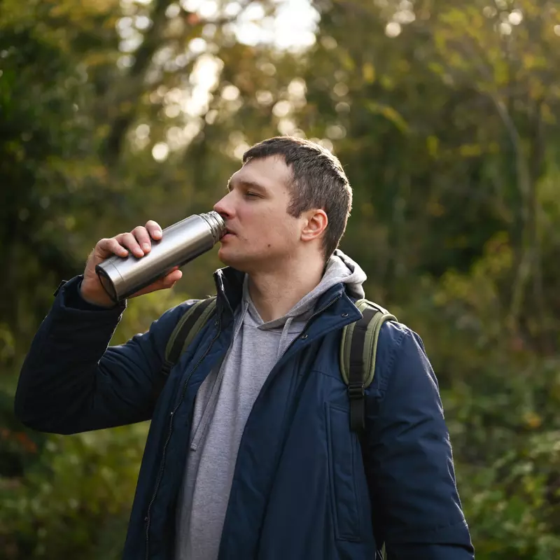 A man drinking water from a metal bottle.