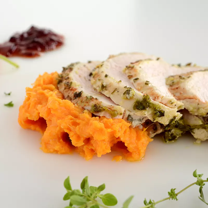 Four slices of turkey breast with sweet potato mash and garnishes