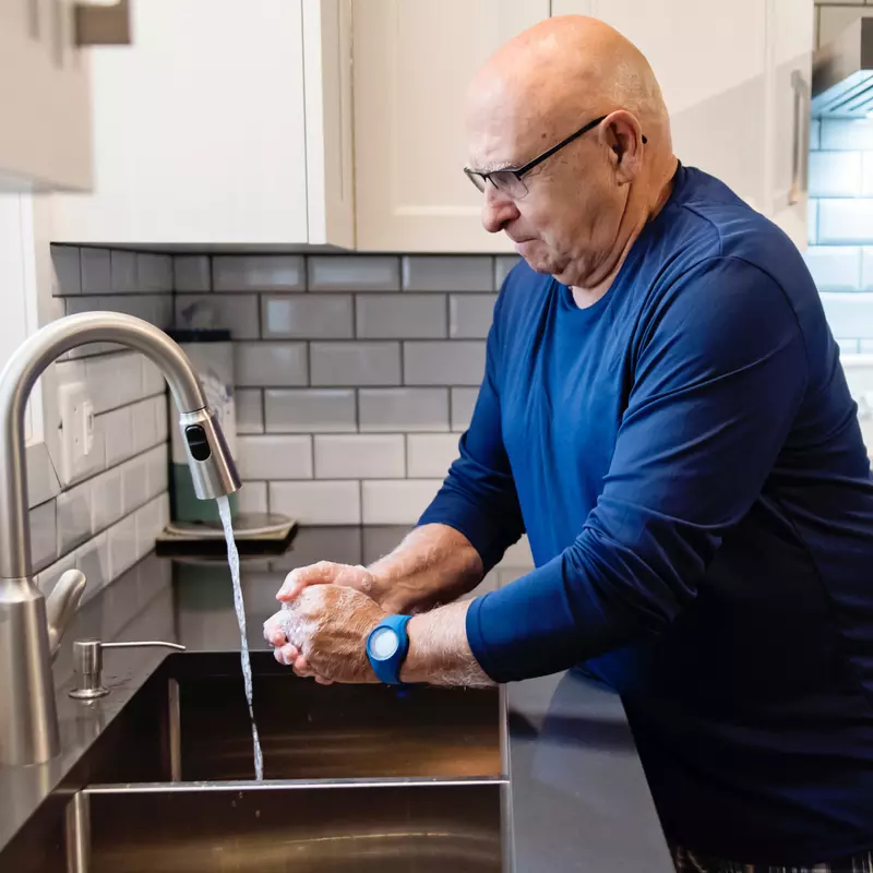 Senior man washing his hands at his home's kitchen sink