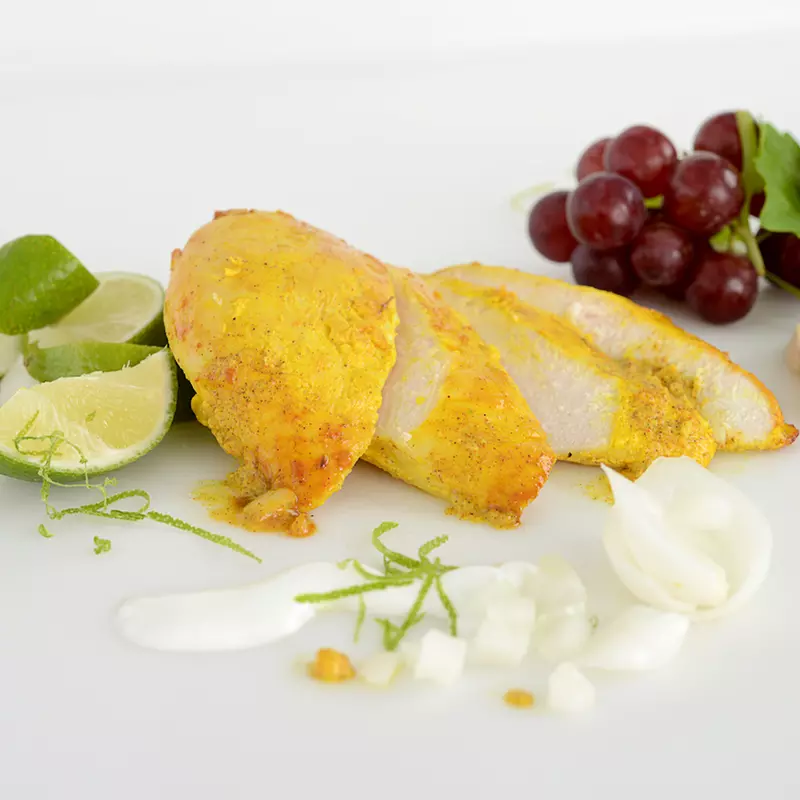 Sliced filet of tandoori chicken with lime and grape garnishes