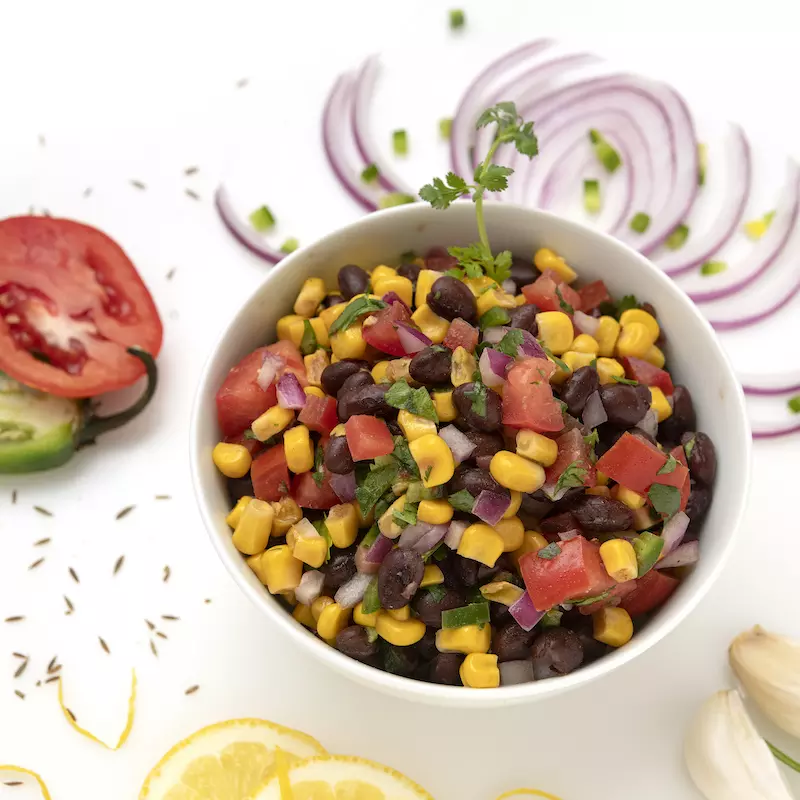 Bowl of black bean salad with vegetable garnishes
