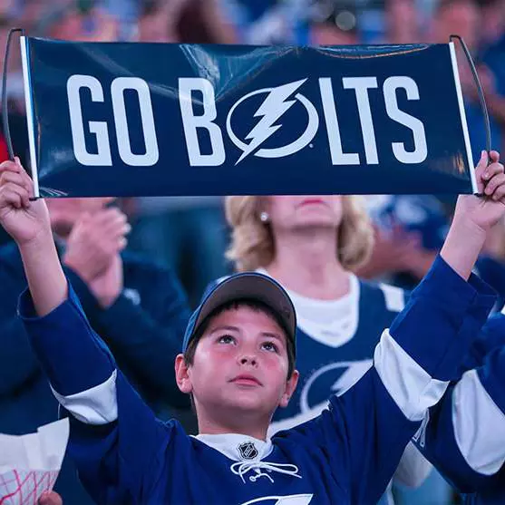 Young Tampa Bay Lightning fan holding a "Go Bolts" sign.
