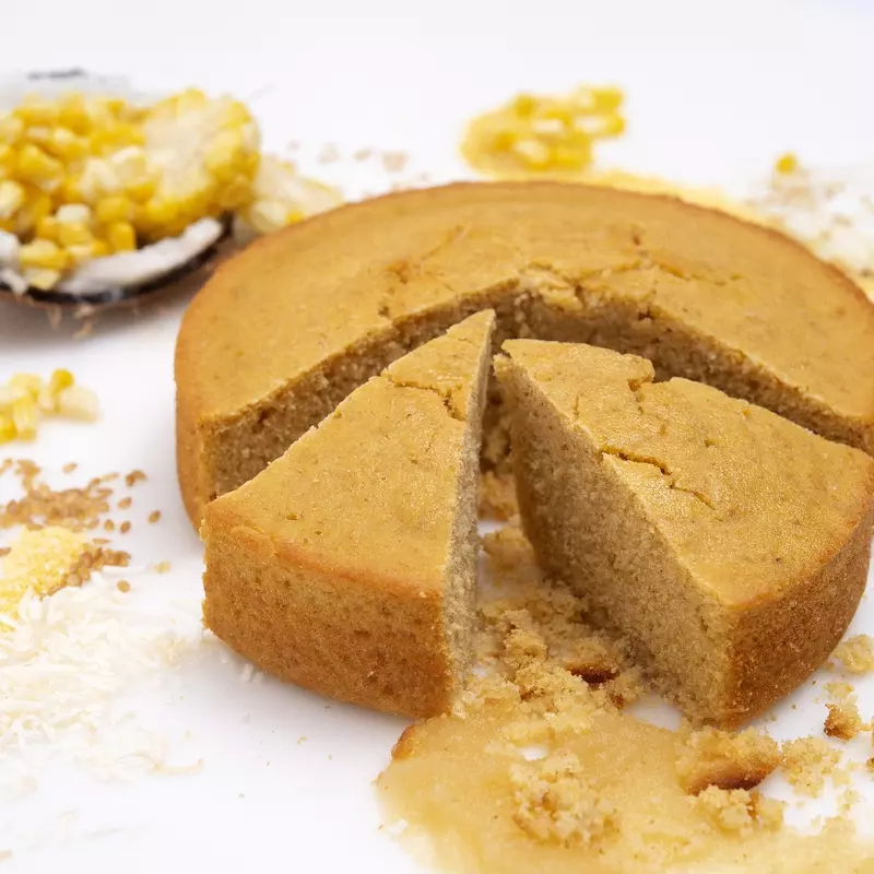 a round loaf of freshly baked cornbread, with two slices cut loose