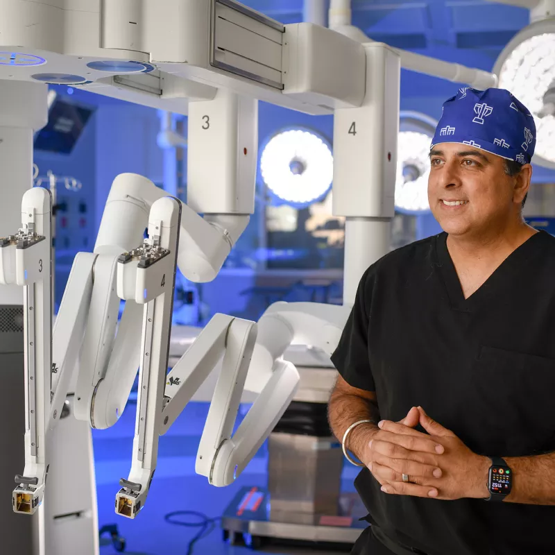 A surgeon standing next to a surgery robot.