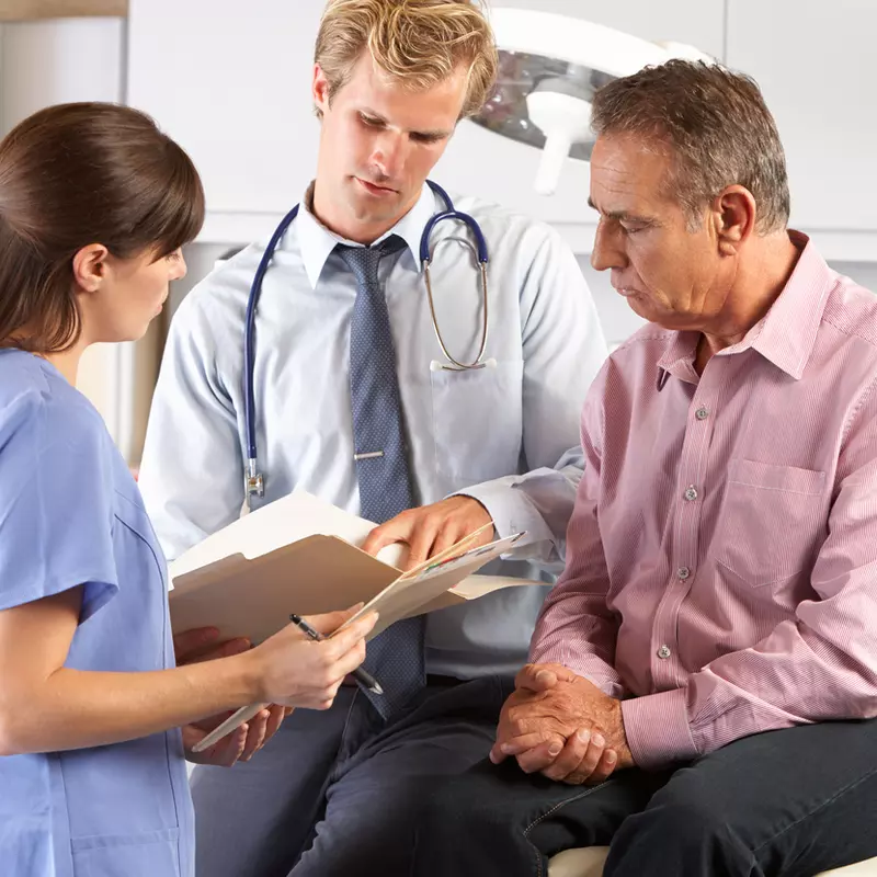 A doctor and a nurse review information with a patient.