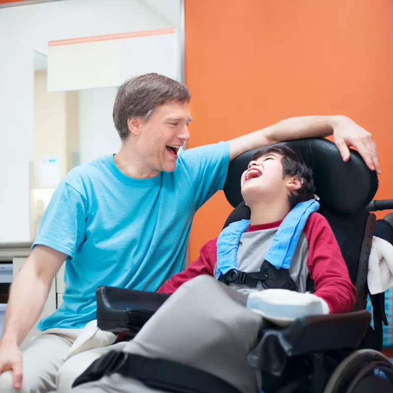 Man and child with cerebral palsy laughing together