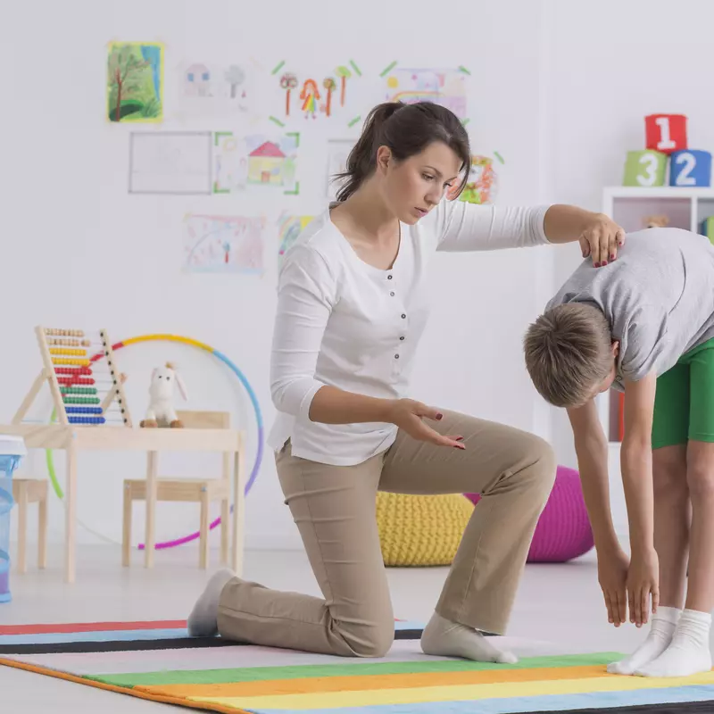 Woman helping boy practice stretching exercises