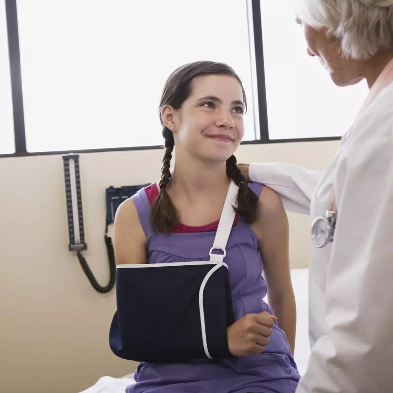 Physician talking to girl with dislocated shoulder