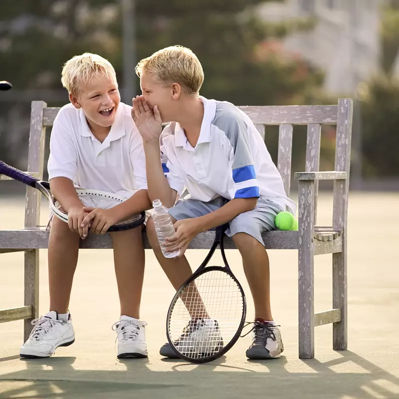 Two boys playing tennis together