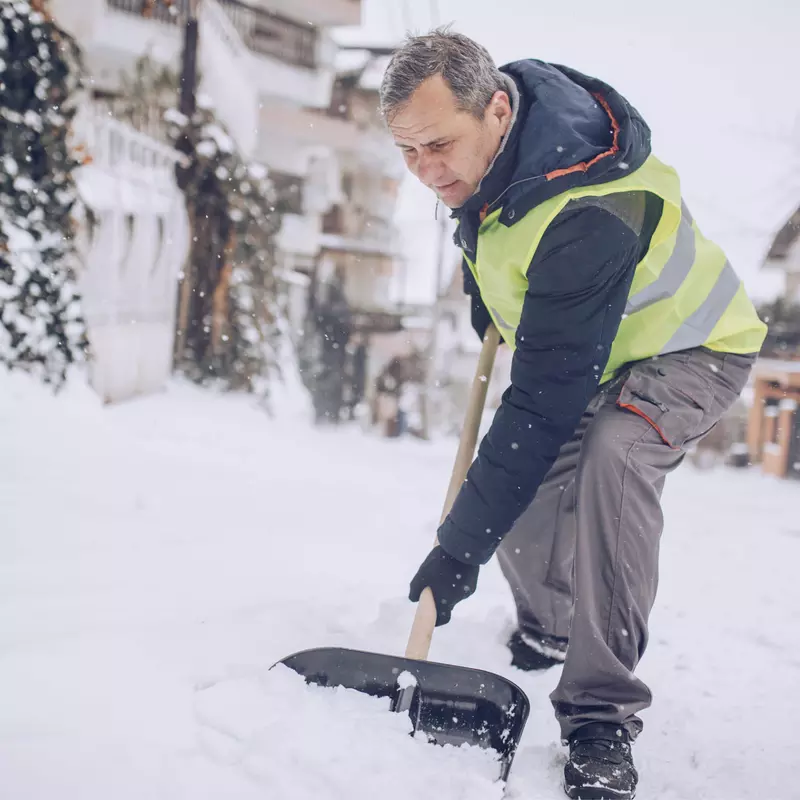 An older man shoveling snow.