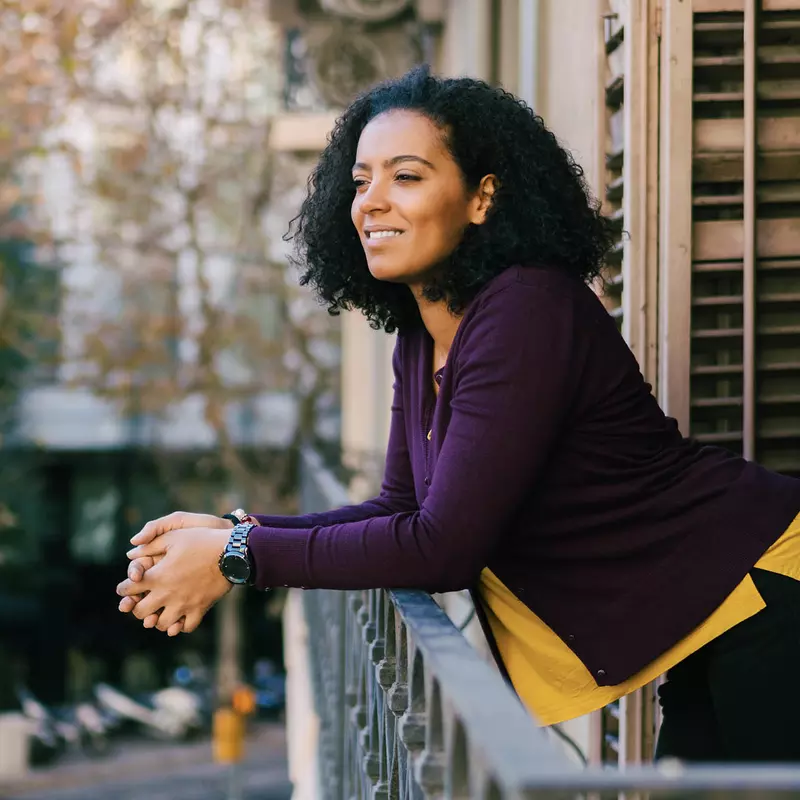 A woman enjoys fresh air on her balcony. 