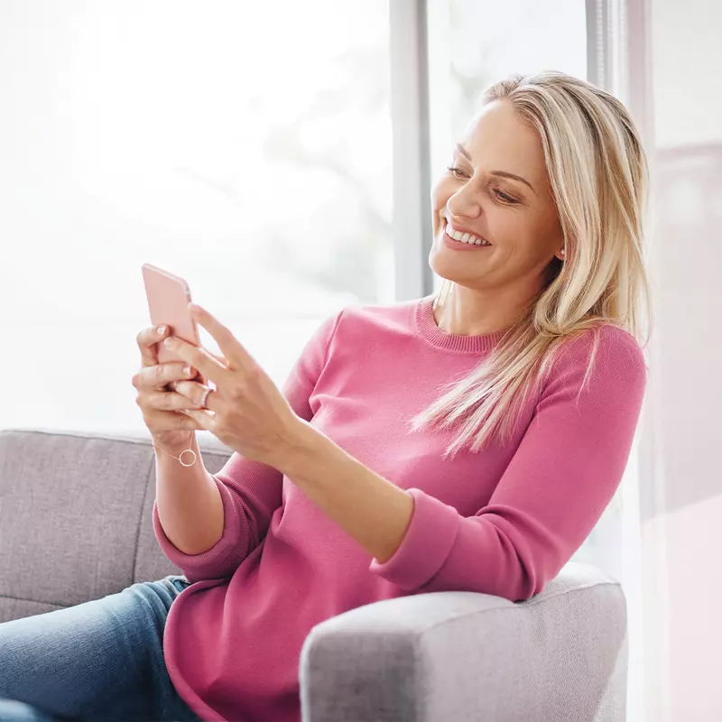 Woman sitting on a couch using a smartphone.