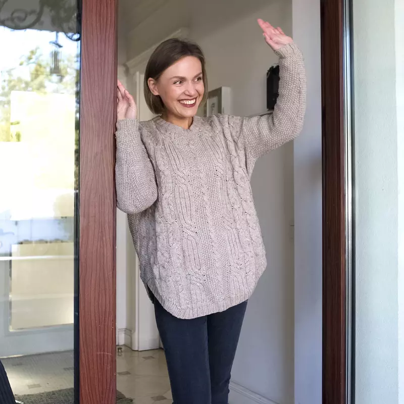 A woman waving at her neighbors from her porch. 